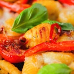 Close-up gnocchi tray bake with sun-dried and fresh tomatoes, mozzarella and pickled chilli.