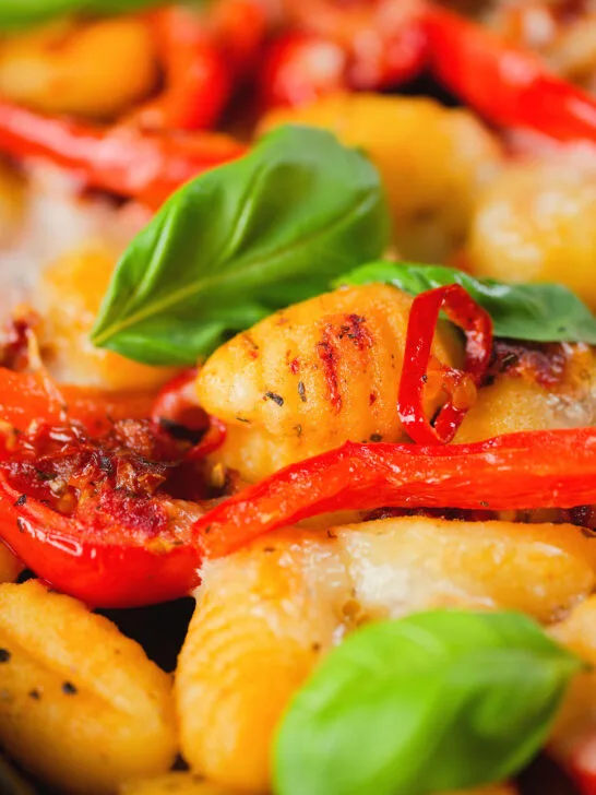 Close-up gnocchi tray bake with sun-dried and fresh tomatoes, mozzarella and pickled chilli.