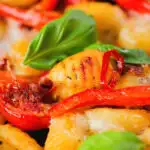 Close-up gnocchi tray bake with sun-dried and fresh tomatoes, mozzarella and pickled chilli.
