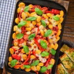 Overhead gnocchi tray bake with sun-dried and fresh tomatoes, mozzarella and pickled chilli.