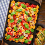 Overhead gnocchi tray bake with sun-dried and fresh tomatoes, mozzarella and pickled chilli.