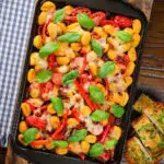 Overhead gnocchi tray bake with sun-dried and fresh tomatoes, mozzarella and pickled chilli.