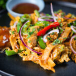 Homemade Sri Lankan chicken kottu (kotthu) roti served on a plate with chutneys.