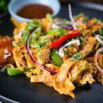 Homemade Sri Lankan chicken kottu (kotthu) roti served on a plate with chutneys.
