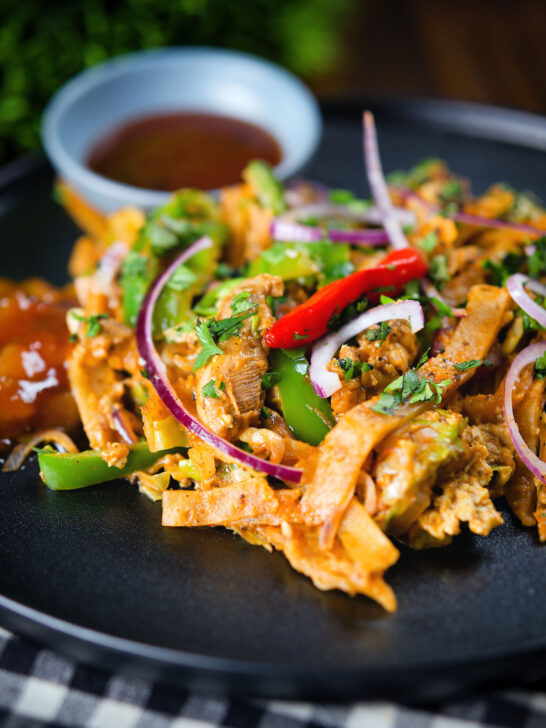 Homemade Sri Lankan chicken kottu (kotthu) roti served on a plate with chutneys.