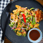 Overhead homemade Sri Lankan chicken kottu (kotthu) roti served on a plate with chutneys.