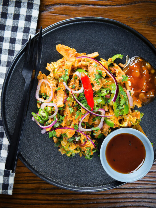 Overhead homemade Sri Lankan chicken kottu (kotthu) roti served on a plate with chutneys.