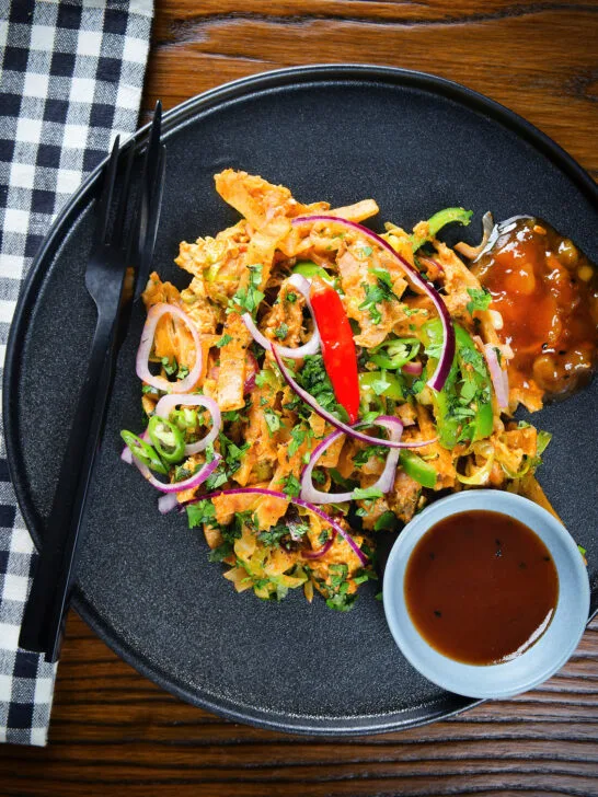 Overhead homemade Sri Lankan chicken kottu (kotthu) roti served on a plate with chutneys.