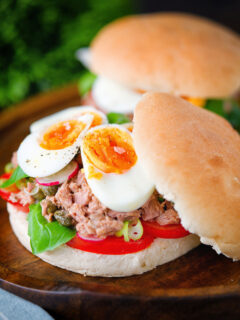 Pan bagnat (French tuna sandwich) with tomatoes, boiled egg and capers on a bread roll.