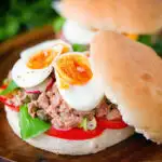 Pan bagnat (French tuna sandwich) with tomatoes, boiled egg and capers on a bread roll.