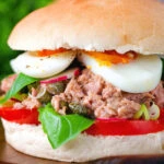 Pan bagnat (French tuna sandwich) with tomatoes, boiled egg, basil, radishes and capers.