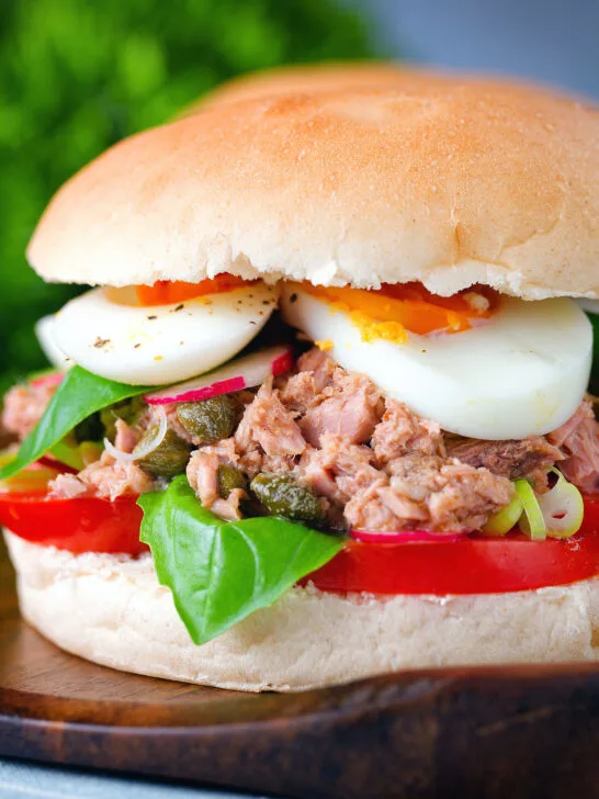 Pan bagnat (French tuna sandwich) with tomatoes, boiled egg, basil, radishes and capers.