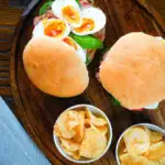 Overhead pan bagnat (French tuna sandwich) with tomatoes, boiled egg and capers on a bread roll.