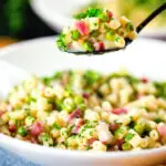 Italian pasta e piselli with peas, pancetta, mint, parsley and ditalini being eaten with a spoon.