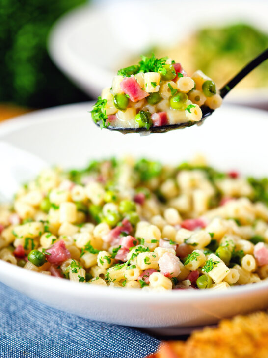 Italian pasta e piselli with peas, pancetta, mint, parsley and ditalini being eaten with a spoon.