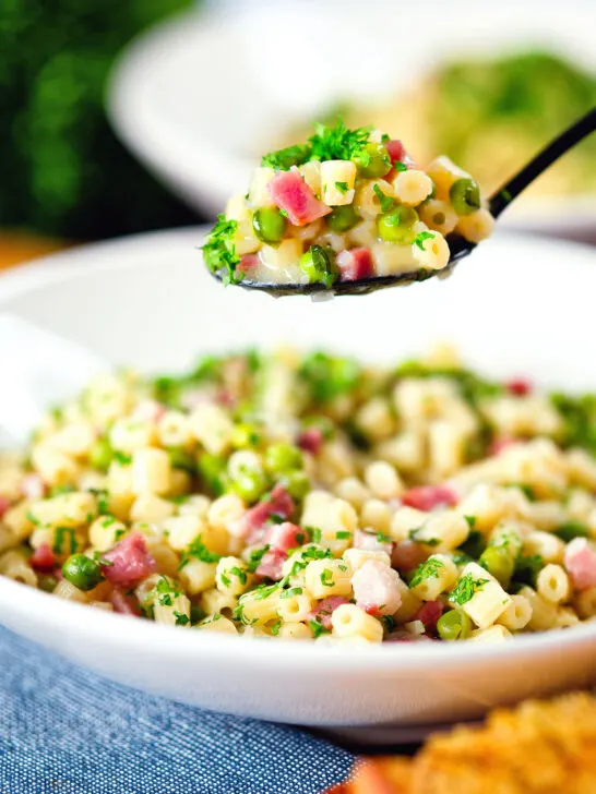 Italian pasta e piselli with peas, pancetta, mint, parsley and ditalini being eaten with a spoon.