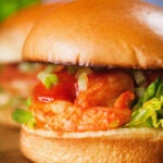 Close-up King prawn sandwich with a bloody Mary sauce and celery on a brioche bun.