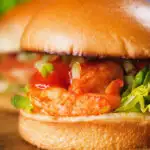 Close-up King prawn sandwich with a bloody Mary sauce and celery on a brioche bun.
