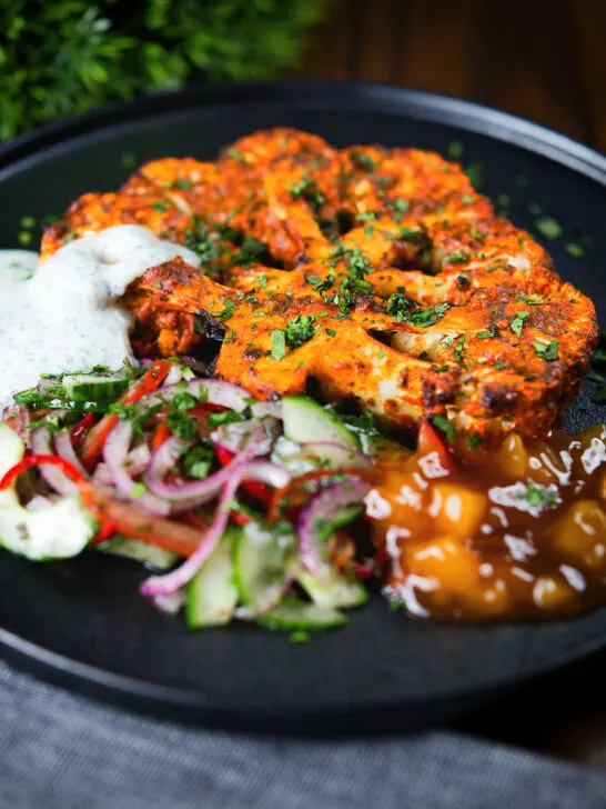 Roasted tandoori cauliflower steak with kachumber salad, mango chutney and mint raita.