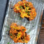 Roasted tandoori cauliflower steaks on a baking tray.