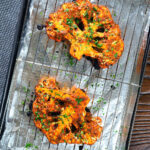 Roasted tandoori cauliflower steaks on a baking tray.