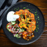 Indian roasted tandoori cauliflower steak served with kachumber salad, mango chutney and raita.