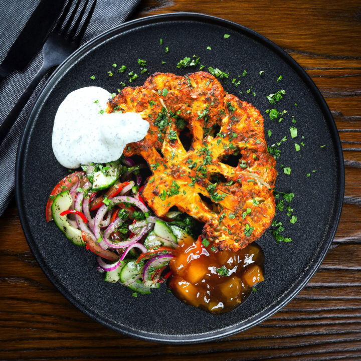 Indian roasted tandoori cauliflower steak served with kachumber salad, mango chutney and raita.