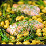 Salmon fillet tray bake with pesto, green veggies and gnocchi served on a sheet pan.