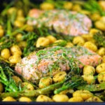 Salmon fillet tray bake with pesto, green veggies and gnocchi served on a sheet pan.