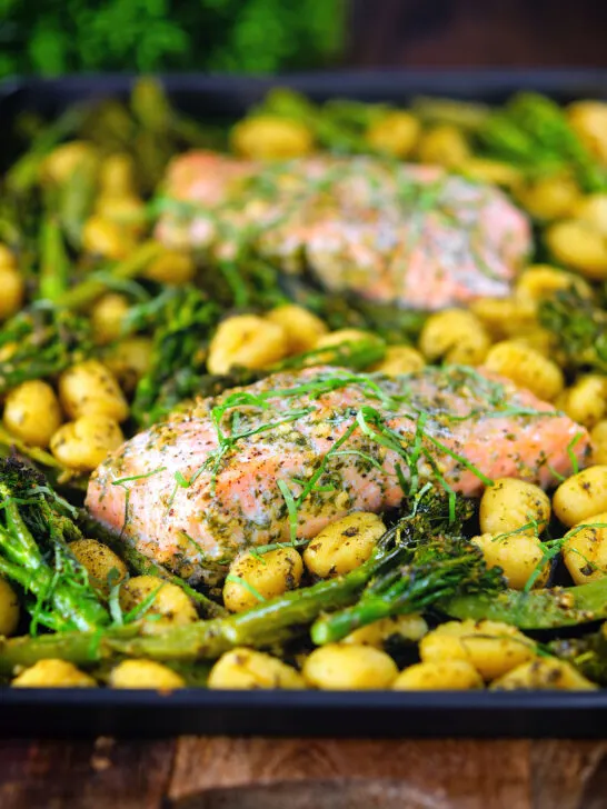 Salmon fillet tray bake with pesto, green veggies and gnocchi served on a sheet pan.