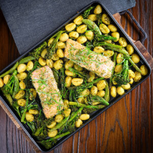 Salmon fillet traybake with gnocchi, basil pesto, asparagus, sugar snap peas and broccoli.