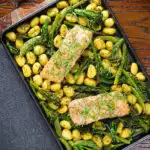 Overhead salmon fillet traybake with pesto, green veggies and gnocchi served on a sheet pan.