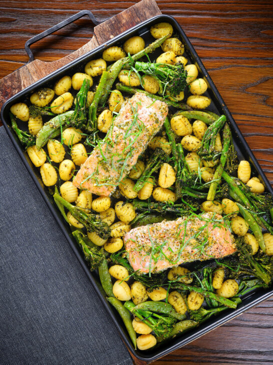 Overhead salmon fillet tray bake with pesto, green veggies and gnocchi served on a sheet pan.