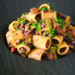 Sardine and tomato pasta Bolognese or ragu garnished with fresh basil.
