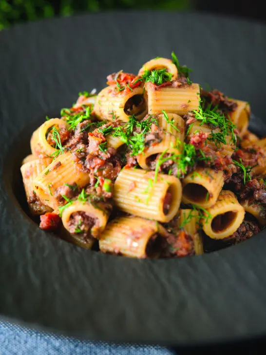 Sardine and tomato pasta Bolognese or ragu garnished with fresh basil.