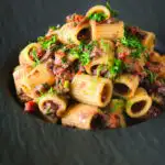 Sardine and tomato pasta Bolognese or ragu garnished with fresh basil.
