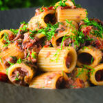 Sardine and tomato pasta (rigatoni) Bolognese or ragu garnished with fresh basil.