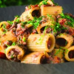 Sardine and tomato pasta (rigatoni) Bolognese or ragu garnished with fresh basil.