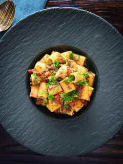 Overhead sardine and tomato pasta Bolognese or ragu garnished with fresh basil.