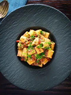 Overhead sardine and tomato pasta Bolognese or ragu garnished with fresh basil.