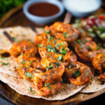 Indian tandoori king prawns skewers with chapatis, kachumber salad and dipping sauces.