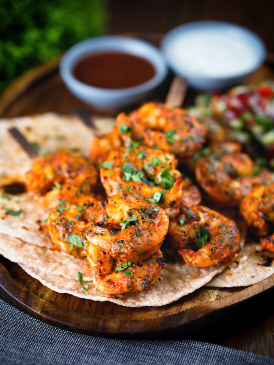 Indian tandoori king prawns skewers with chapatis, kachumber salad and dipping sauces.