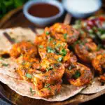 Indian tandoori king prawns skewers with chapatis, kachumber salad and dipping sauces.