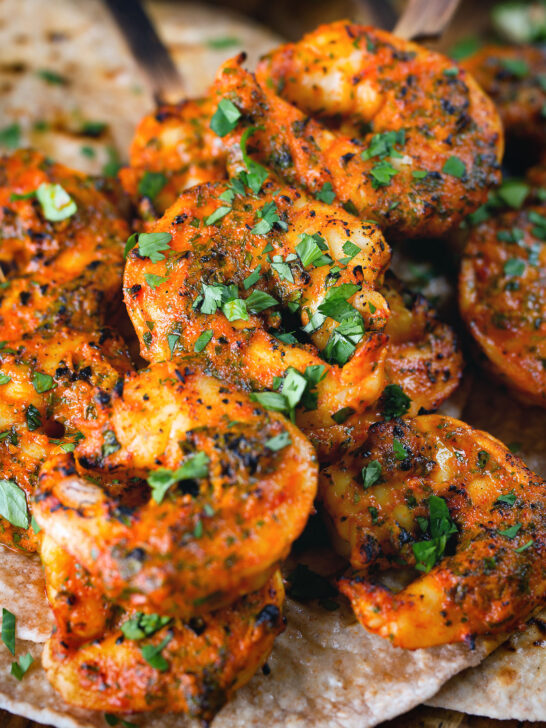 Close-up Indian tandoori king prawns skewers served with chapatis.