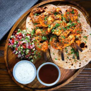 Indian tandoori king prawns with chapatis, kachumber salad, mint raita and tamarind chutney.