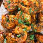 Overhead close-up Indian tandoori king prawns skewers served with chapatis.