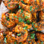 Overhead close-up Indian tandoori king prawns skewers served with chapatis.