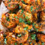 Overhead close-up Indian tandoori king prawns skewers served with chapatis.