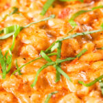 Close-up tomato and mascarpone cheese risotto with basil chiffonade.
