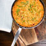 Overhead tomato and mascarpone cheese risotto with basil chiffonade served in a cooking pan.